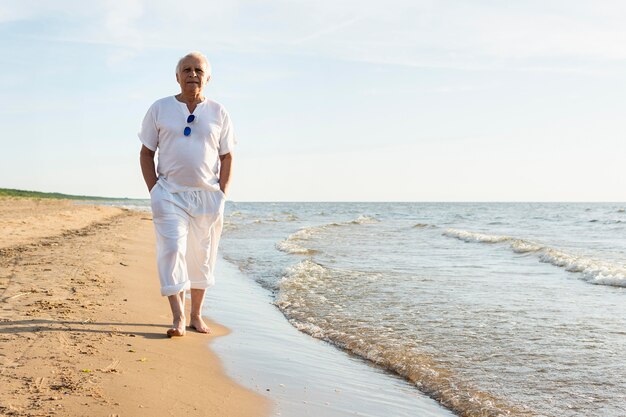 Oudere man wandelen langs het strand genieten van het uitzicht
