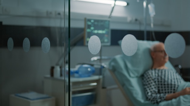 Oudere patiënt met ziekte zittend in ziekenhuisafdeling