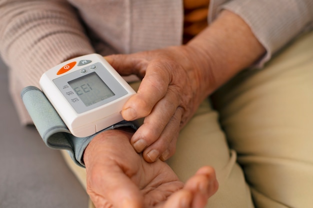 Gratis foto oudere persoon die zijn bloeddruk controleert met een tensiometer