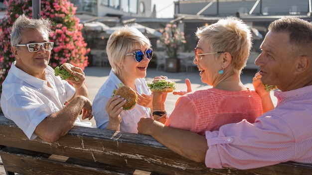 Oudere stellen die hamburgers eten op het strand