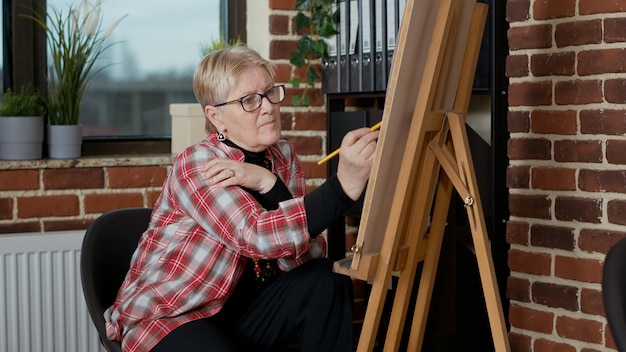 Oudere student die potlood op canvas gebruikt om een tekening te maken op het kunstacademieprogramma, de les bij te wonen om nieuwe artistieke vaardigheden te ontwikkelen voor persoonlijke groei. Schets de praktijk met gereedschappen en instrumenten.