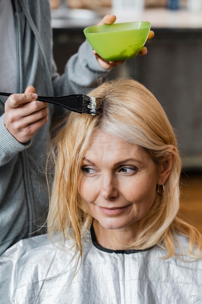 Gratis foto oudere vrouw die haar haar thuis door kapper krijgt geverfd