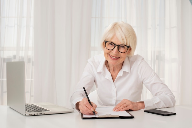 Oudere vrouw die in een klembord schrijft