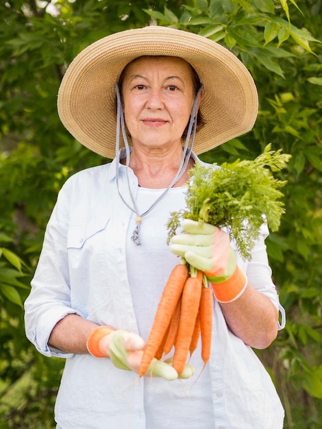 Oudere vrouw die wat verse wortelen in haar hand houdt