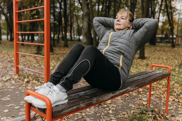 Oudere vrouw doet crunches buitenshuis