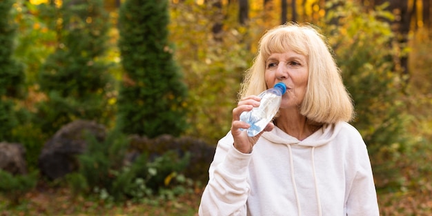 Gratis foto oudere vrouw drinkwater buitenshuis