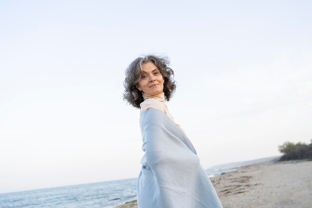 Oudere vrouw geniet van haar tijd op het strand