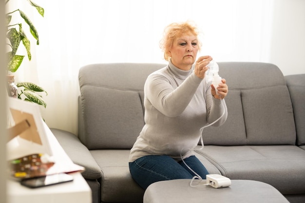 Oudere vrouw met astma machine op lichte achtergrond.