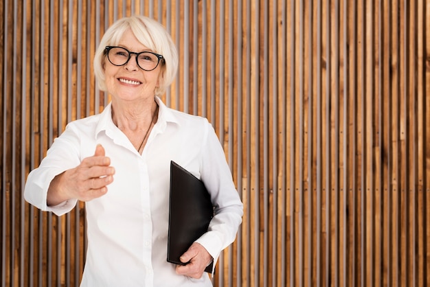 Oudere vrouw met een klembord op houten achtergrond