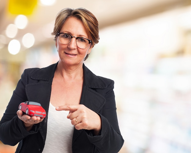 Gratis foto oudere vrouw met een rode auto