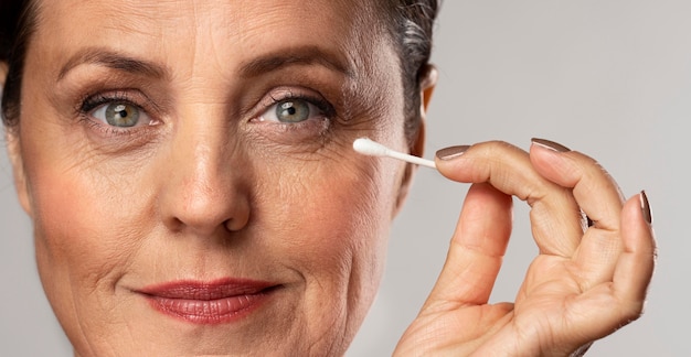 Oudere vrouw met make-up op het gebruik van een wattenstaafje om het te verwijderen