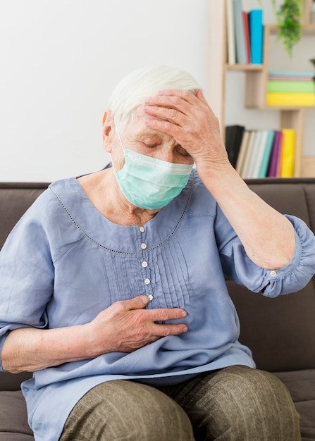 Oudere vrouw met medisch masker ziek voelen