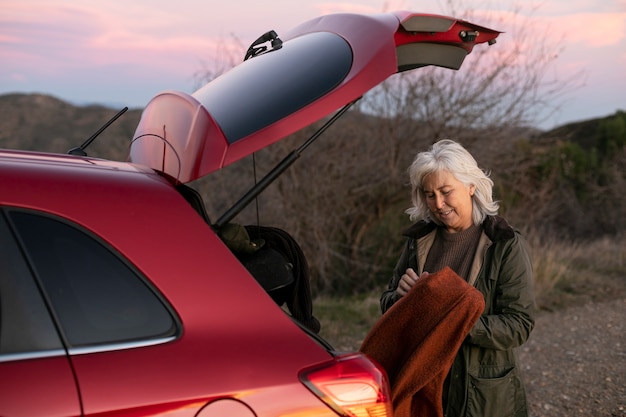 Oudere vrouw op avontuur in de natuur met haar auto