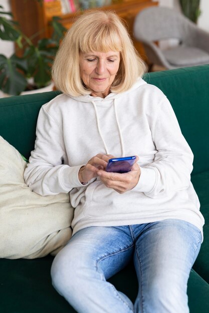 Oudere vrouw thuis op de bank met smartphone