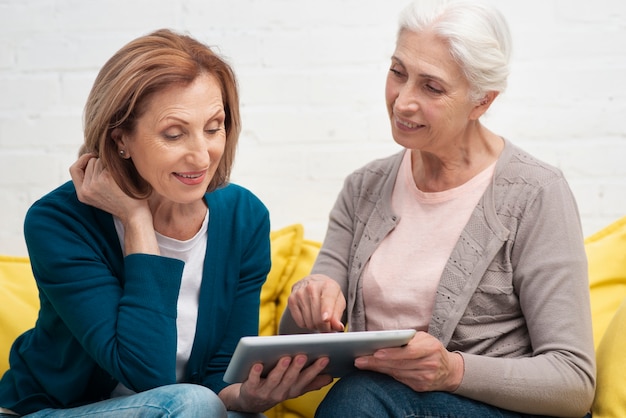 Gratis foto oudere vrouwen die een tablet doorbladeren