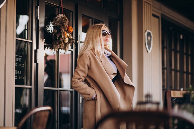 Oudere zakenvrouw in een jas buiten het café