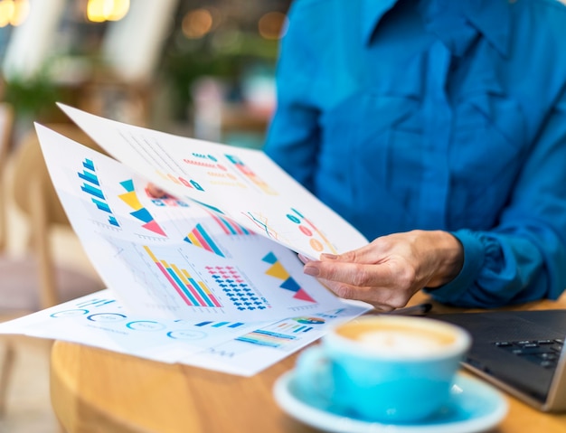 Gratis foto oudere zakenvrouw omgaan met papier terwijl het hebben van een kopje koffie