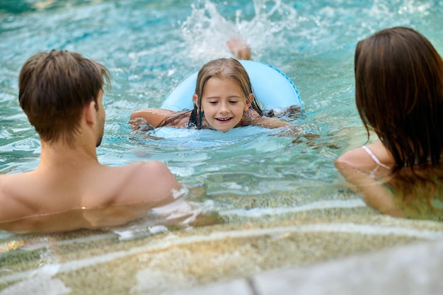 Ouders die hun dochter leren zwemmen en er betrokken bij kijken