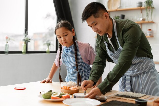 Gratis foto ouders die hun kind sushi leren maken.