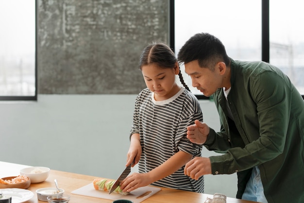 Gratis foto ouders die hun kind sushi leren maken.