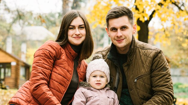 Ouders en kleine dochter zitten in de herfst park