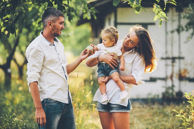 Ouders met baby genieten van picknick op een boerderij met appel- en kersenbomen.