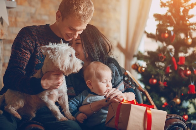 Ouders met een hond en een baby met een kerst boom achtergrond