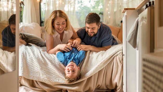 Ouders spelen met hun zoon in het bed van een caravan