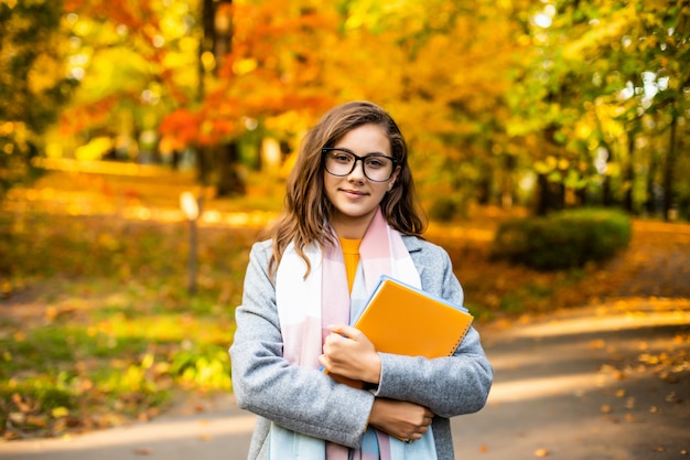 Outdoor herfst portret gelukkig lachend tienermeisje met schriften