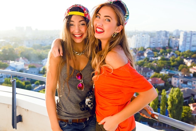 Outdoor lifestyle portret van twee beste duivels zusters meisjes die zich voordeed op het dak