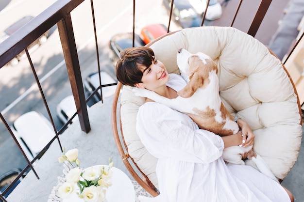 Outdoor portret van bovenaf van speelse beagle ligt in stoel naast lachend meisje