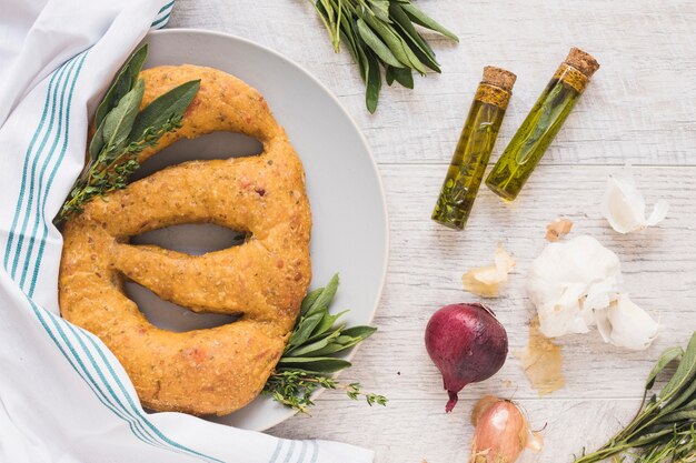 Ovaal vorm gebakken brood met kruiden en ingrediënten op houten plank