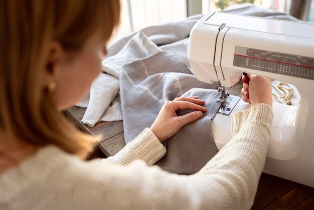 Over de schouder weergave van kleermaker vrouw met behulp van naaimachine