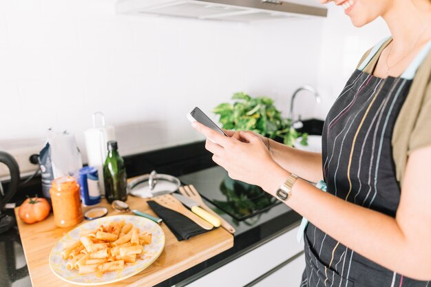 Overhandigt jonge vrouw die foto van heerlijke deegwaren op smartphone nemen