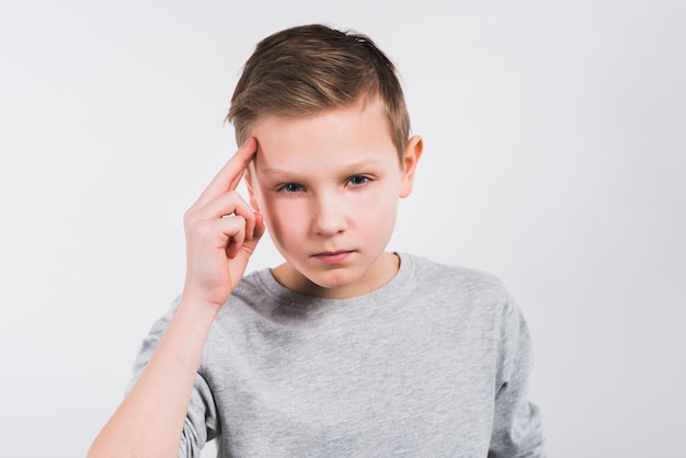 Overpeinsde jongen die aan camera kijkt die zich tegen grijze achtergrond bevindt