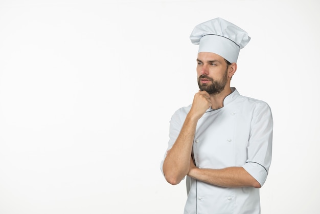 Overwogen jonge mannelijke die chef-kok op witte achtergrond wordt geïsoleerd