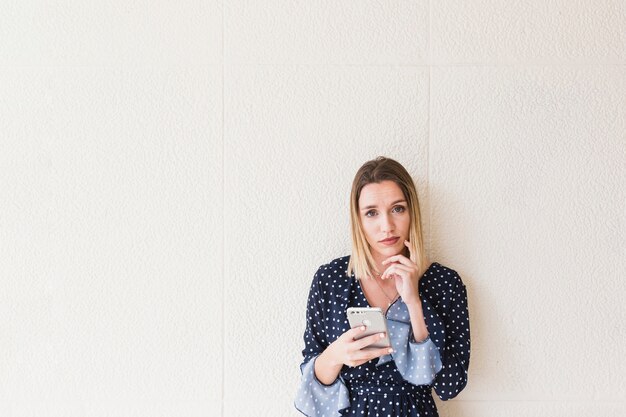 Overwogen jonge vrouw met mobiele telefoon camera kijken