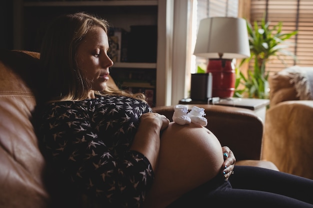 Paar babysokken op zwangere vrouwenmaag in woonkamer