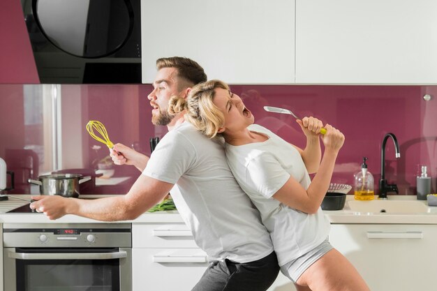 Paar binnenshuis zingen in de keuken zitten zijdelings