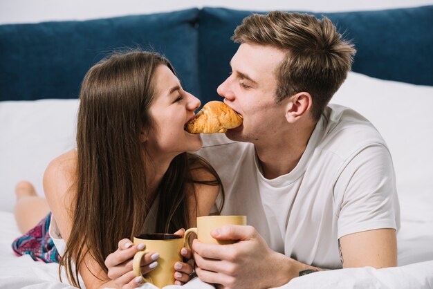 Paar dat één croissant in bed eet