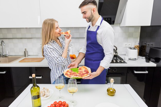 Paar dat gekookte pizza in keuken eet