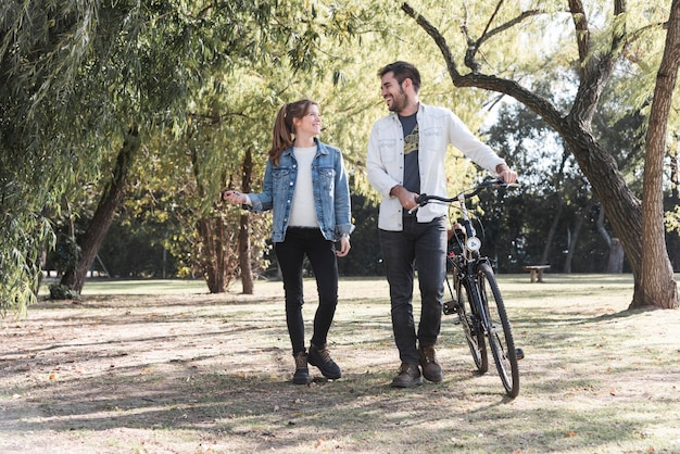 Paar dat met fiets in park loopt