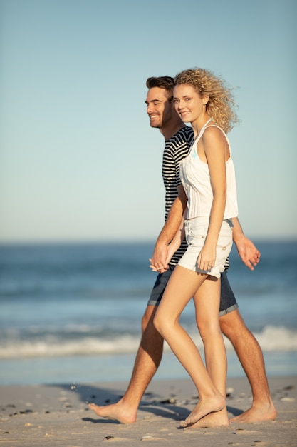 Paar dat samen hand in hand op het strand loopt