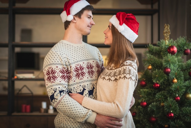 Paar dat santahoeden draagt die elkaar omhelzen