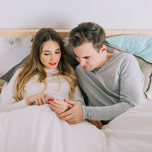 Paar dat smarthone in bed bekijkt