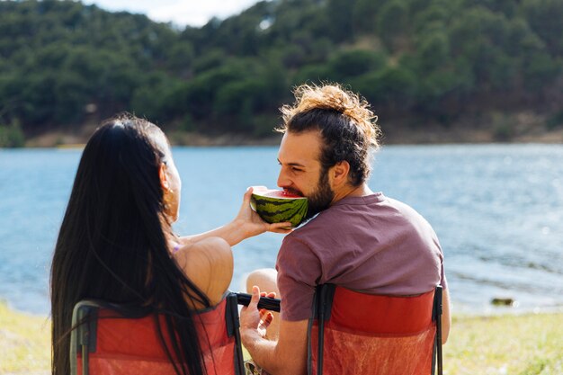 Paar dat watermeloen op rivierkust eet