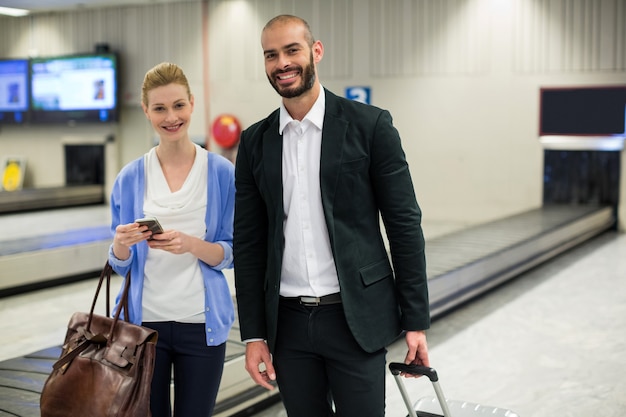 Paar dat zich met bagage bij wachtruimte op luchthaven bevindt