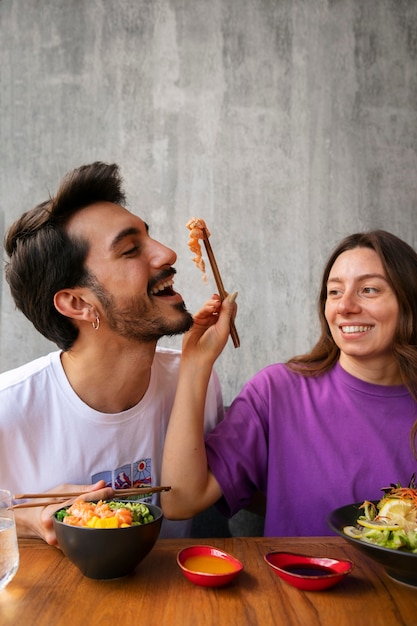 Gratis foto paar die de kom van de zalmschotel eten bij het restaurant