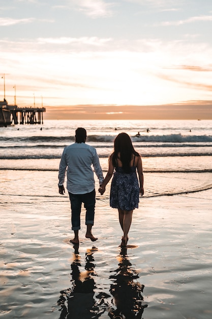 Paar hand in hand met elkaar tijdens het wandelen aan de kust overdag