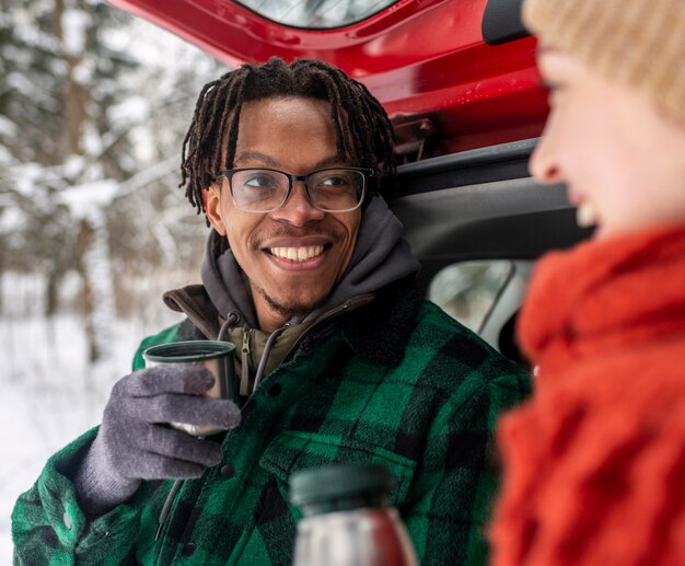 Paar het drinken van thee zittend op de kofferbak van de auto